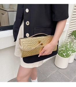 Detail of woven metallic gold handbag with Intrecciato pattern and metal clasp closure