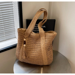 Detail of straw woven tote bag featuring a decorative tassel with wooden beads
