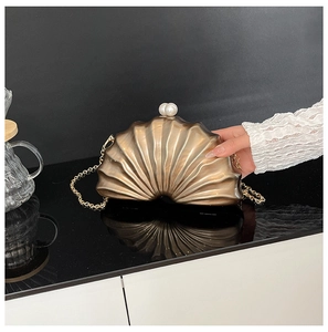 Détail de la pochette de soirée en forme de coquille dorée avec fermoir en perles