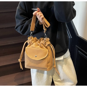 Close-up of khaki canvas bucket bag with drawstring closure and wide shoulder strap on model