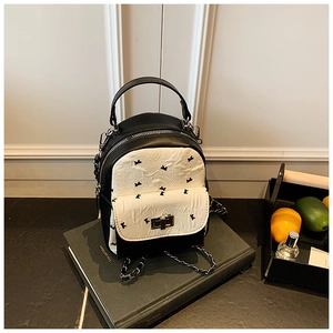 Close-up of a quilted mini backpack with contrast embroidery and silver twist lock detail