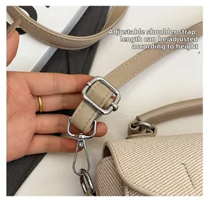 Detail of adjustable leather strap with silver buckle on beige woven handbag