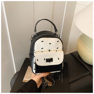 Close-up of mini quilted backpack with black bird pattern and metal twist lock detail