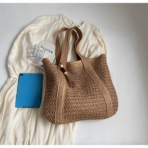 Detail view of straw tote bag showing intricate woven texture and decorative tassel