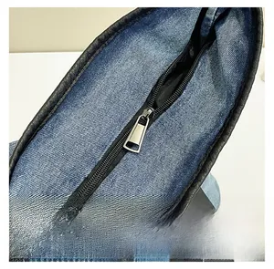 Close-up of denim tote bag featuring secure silver metal zipper and black leather piping