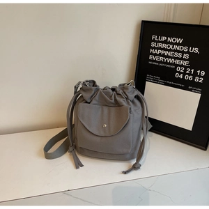 Detail view of grey canvas bucket bag with drawstring closure and metal buckle pocket