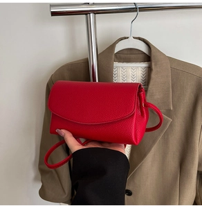 Detail of red lychee textured leather crossbody bag with a stylish flap closure