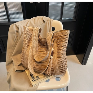 Detailed close-up of woven straw tote bag texture with tassel and wooden bead charms