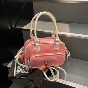 Pink and white Boston style crossbody bag with top handles shown in a hand-held pose
