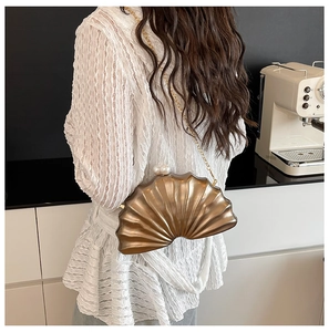 Détail du sac bandoulière métallique en forme de coquillage avec fermoir perlé et chaîne