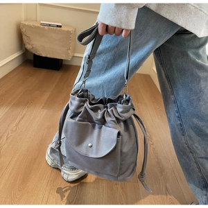 Detail showing grey canvas bucket bag with drawstring closure and silver hardware accents