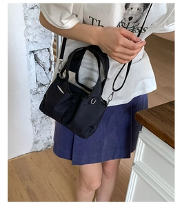 Detail of black nylon handbag with white stitching and detachable shoulder strap