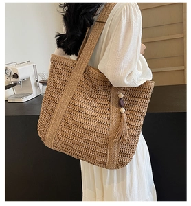 Detail of hand-woven straw shoulder bag with stylish fringe and decorative wood beads
