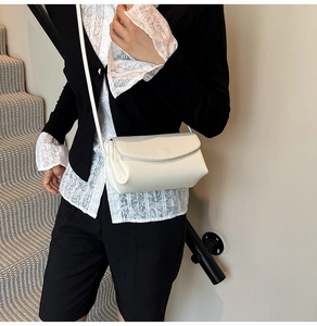 Close-up of white litchi textured crossbody bag with minimalist flap design on model