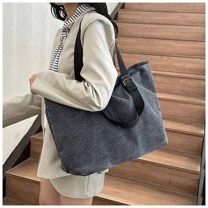 Detail of grey canvas tote bag showing wide nylon strap and adjustable metal buckle