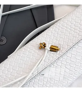 Detail of white woven leather texture with an elegant gold-tone metal knot buckle