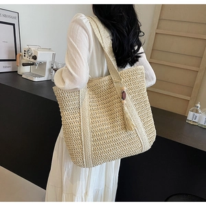 Detail of straw woven tote bag with wooden beads and tassel charms in a cafe setting