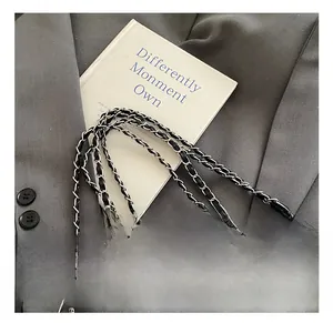 Detail shot of the leather-woven silver chain strap against a grey suit and prop book