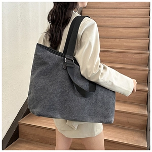 Deep grey canvas tote bag with black straps shown on a model on wooden stairs