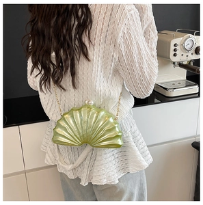 Détail du sac en acrylique vert citron en forme de coquille avec chaîne dorée et perle
