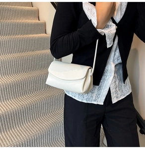 Close-up of white crossbody bag with lychee texture leather on a model's outfit