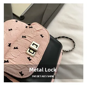 Detail of a pink quilted bag with a black K-pattern and golden metal twist lock closure