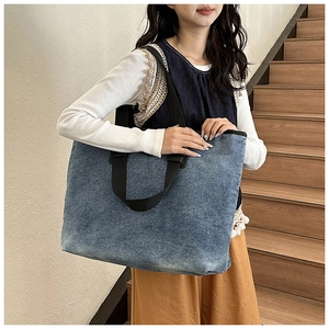 Detailed view of the large denim tote bag featuring wide black fabric shoulder straps