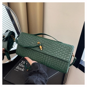 Detailed view of dark green woven texture leather bag with gold twist lock and shoulder strap