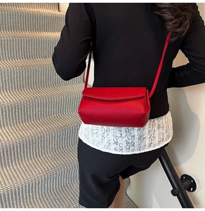 Model wearing a red lychee texture leather crossbody bag on a minimalist staircase