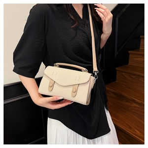 Detail of beige woven handbag with leather straps and decorative buckles on steps