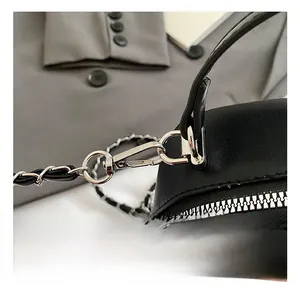 Macro shot of silver metal swivel hooks and chain strap on black quilted leather backpack