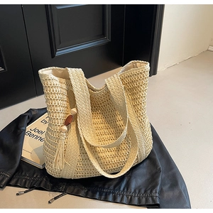 Detailed close-up of ivory woven straw tote bag with decorative fringe and wooden beads