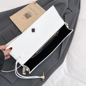 Interior view of white woven baguette bag showing main compartment and gold hardware detail