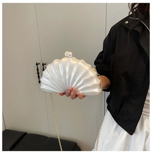 Détail d'une pochette de soirée coquillage blanc perle avec fermoir perle et chaîne dorée
