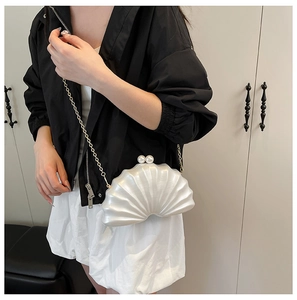 Détail d'une pochette de soirée coquillage blanc avec fermoir perle et chaîne dorée femme