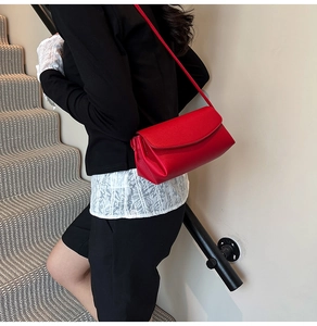 Close-up of bright red lychee textured leather flap bag worn by a model on shoulder