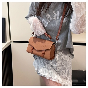 Detail of retro tan crossbody bag showing textured grain material and double buckle design