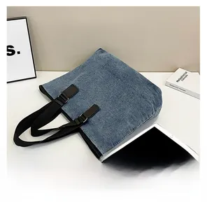 Detailed view of durable blue denim tote bag with adjustable black webbing shoulder straps