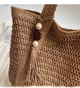 Detail of woven straw tote bag featuring bohemian wooden beads and long tassels decoration