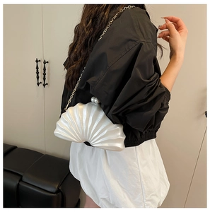 Détail du sac de soirée blanc perle en forme de coquillage avec fermoir et chaîne dorée