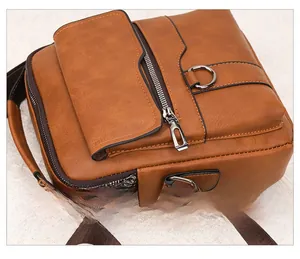 Detail view of the smooth metallic zippers and fine stitching on the brown leather bag