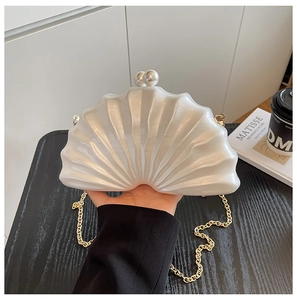 Vue détaillée de la pochette coquillage blanc nacré avec chaîne dorée et fermoir perle