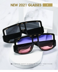 Close-up of oversized square sunglasses with gold rivet details on black and purple frames