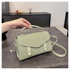Detail of mint green textured handbag featuring dual vertical straps and a round buckle