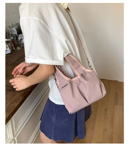 Detail of light purple canvas crossbody bag showing metal buckle and soft texture