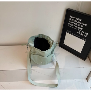Top view of a light green canvas bucket bag with a front flap pocket on marble
