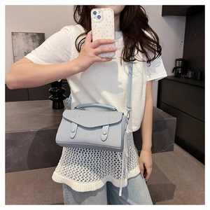 Close-up of a light blue textured fabric crossbody bag with double button detail