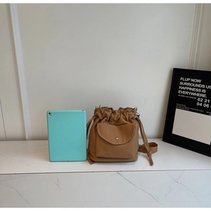 Size comparison of a camel canvas drawstring bucket bag next to a blue tablet device