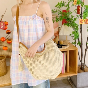 Handwoven beige beach tote bag with brown leather straps and stylish tassel charm