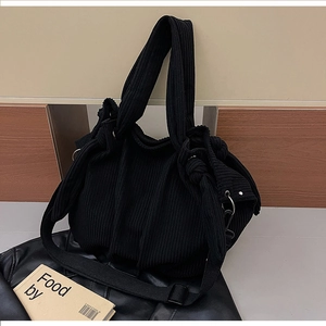 Detail of black corduroy dumpling bag featuring wide pleated texture and side knot detail